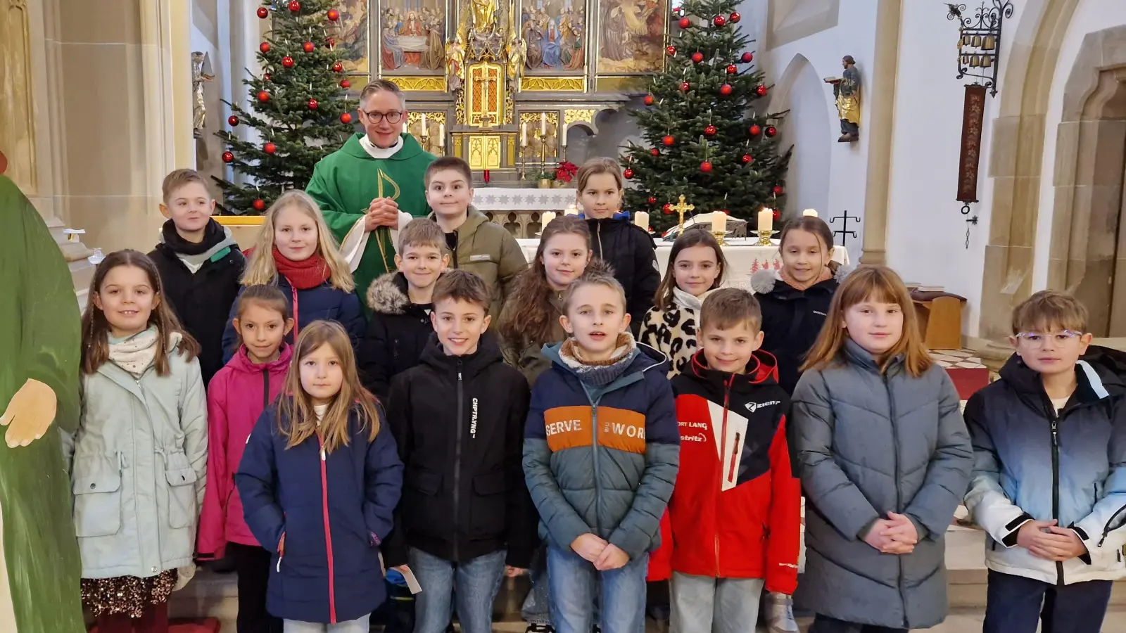 Die Grundschulkinder und Pfarrer Adam Karolczak neben einer Jesus-Statue mit der Aufschrift „Ihr seid meine Freunde”. (Bild: Felix Hartung)