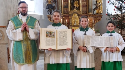 Pfarrer Johannes Arweck und die Ministrantinnen zeigen die kostbare Bibel und die Schriftrolle. (Bild: Theresia Otterbein)