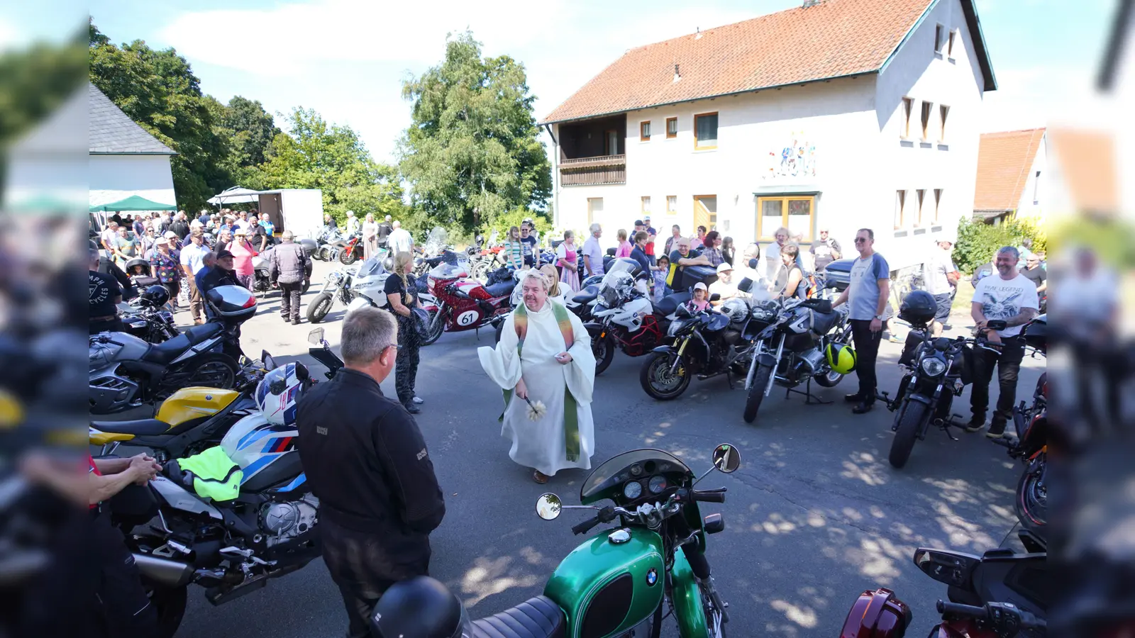 Pfarrer Albert Hölzl versprüht nach dem Motorradgottesdienst Freude und Weihwasser und segnet die Motorräder.<br> (Bild: Franz Völkl)
