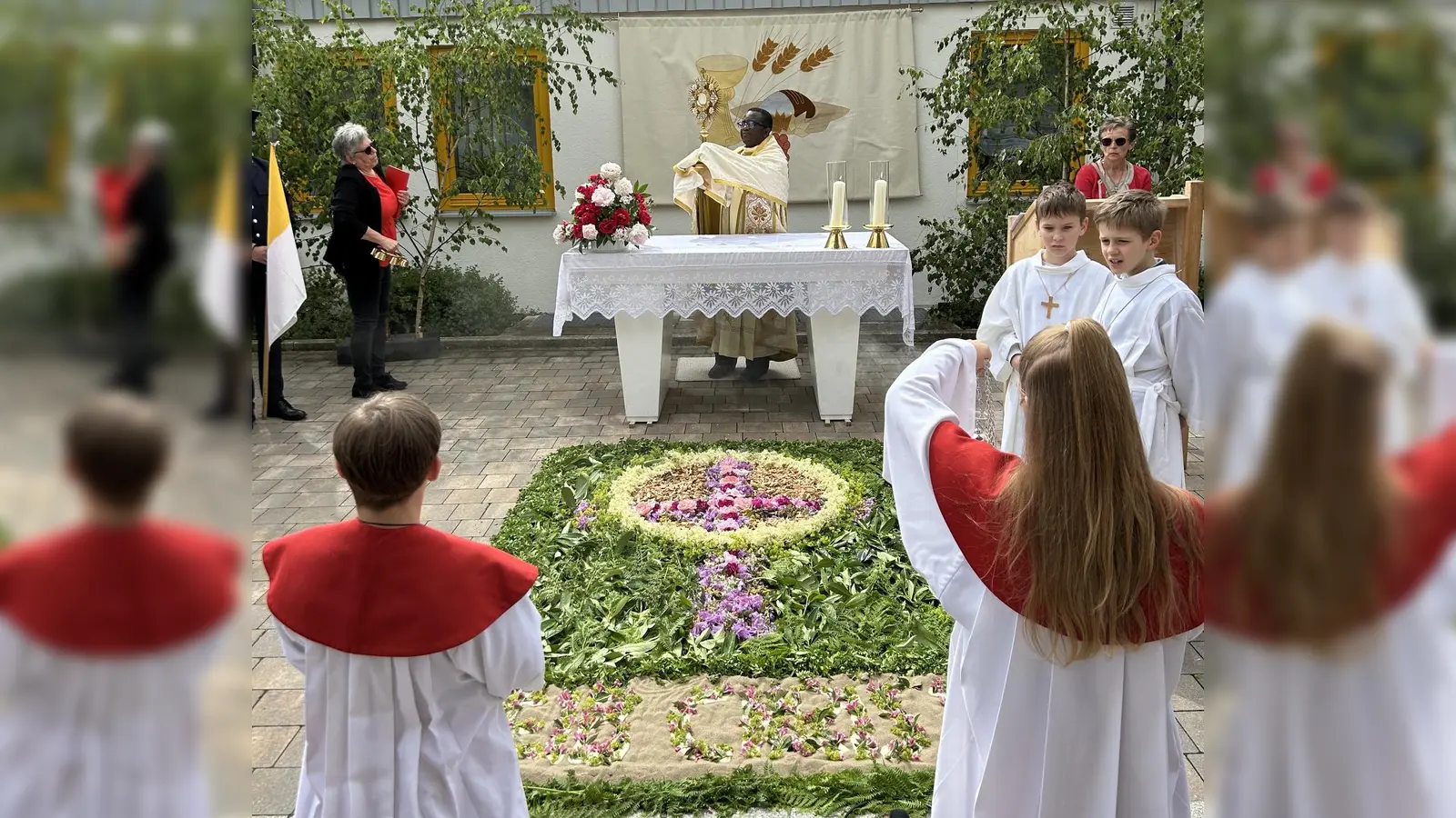 Am bunt geschmückten Blumenaltar am katholischen Kindergatren feierte Pfarrvikar Dr. Linus zusammen mit über hundert Gläubigen eine kleine Andacht. (Bild: Roman Melzner )
