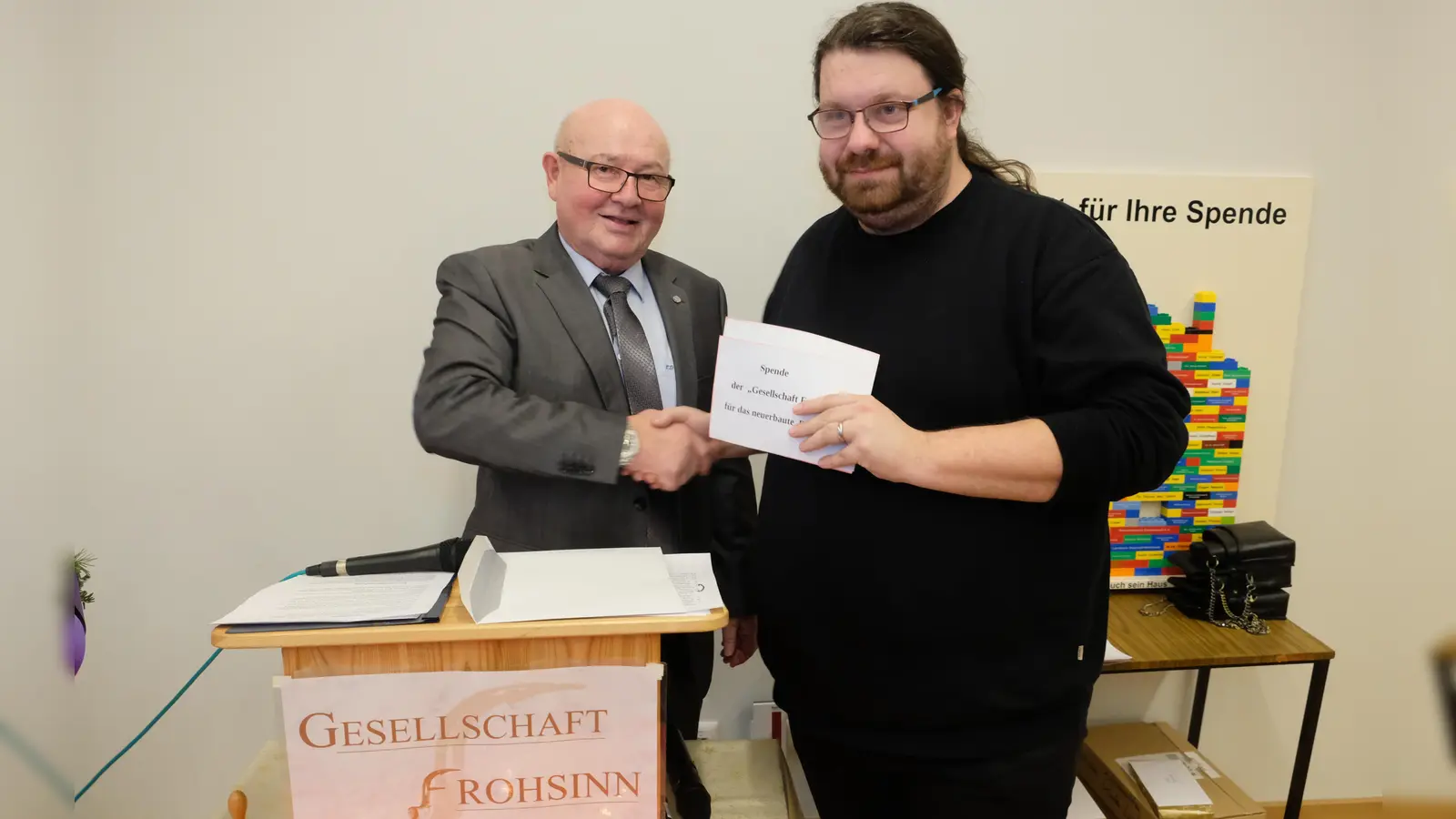 Frohsinn-Präsident Erwin Dromann (li) übte sich gleichzeitig als Nikolaus und Christkindl bei der Spendenübergabe an Stadtpfarrer Johannes Bosco.  (Bild: Robert Dotzauer)