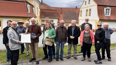 Die Walmdächer des Schlosses von Ebermannsdorf bildeten ein wunderbaren Hintergrund am Ende der Exkursion. Der Immobilienmakler und Burgenspezialist Matthias Helzel (2.v.li.) überreichte dem Freiherr Eckart von Eyb (5.v.li.) eine historische Karte. (Bild: Marianne Moosburger)