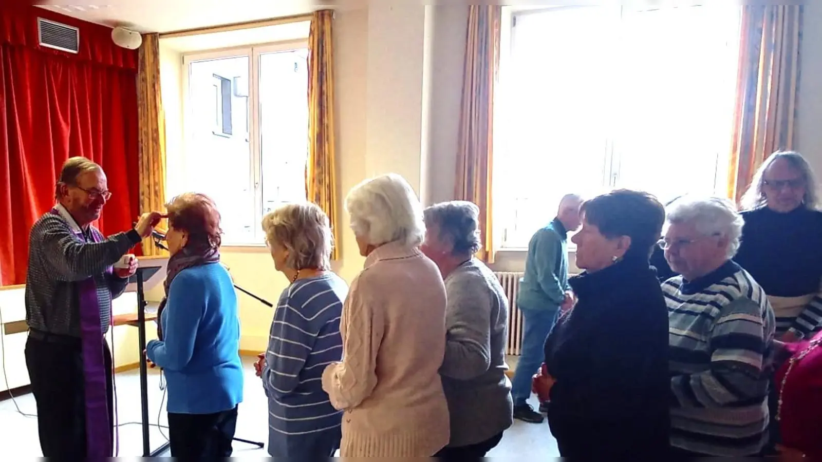 Pfarrer Thomas Stohldreier zeichnet das Aschenkreuz auf die Stirn der Senioren. (Bild: Sabine Bäumler)