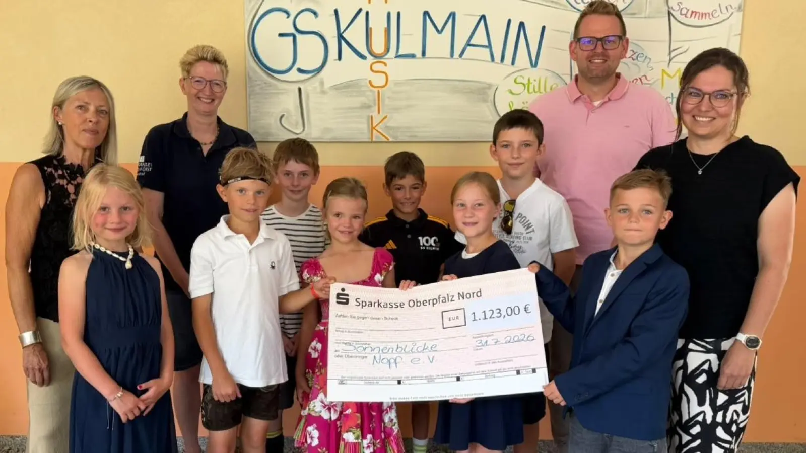 Daniela und Marco Pscherer vom Team „Sonnenblicke e.V.”, Schulleiterin Christiane Böhm, Initiatorin der BallHelden-Aktion Christine Dötsch und Kinder der GS Kulmain bei der Übergabe des Spendenschecks. (Bild: Sandra Schraml)
