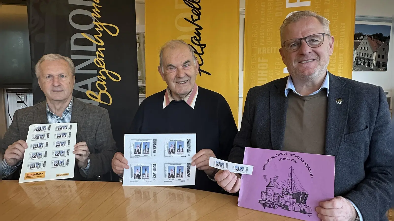 Hans Müller (1. Vorstand der Briefmarkenfreunde Schwandorf e.V., links) und Leonhard Reith (Organisationsleiter Briefmarkenfreunde Schwandorf e.V., Mitte) präsentieren Oberbürgermeister Andreas Feller (rechts) die speziell zum 60-jährige Städtepartnerschaftsjubiläum zwischen Schwandorf und Libourne kreierte Sonderbriefmarke. (Bild: Lara Schmaus)