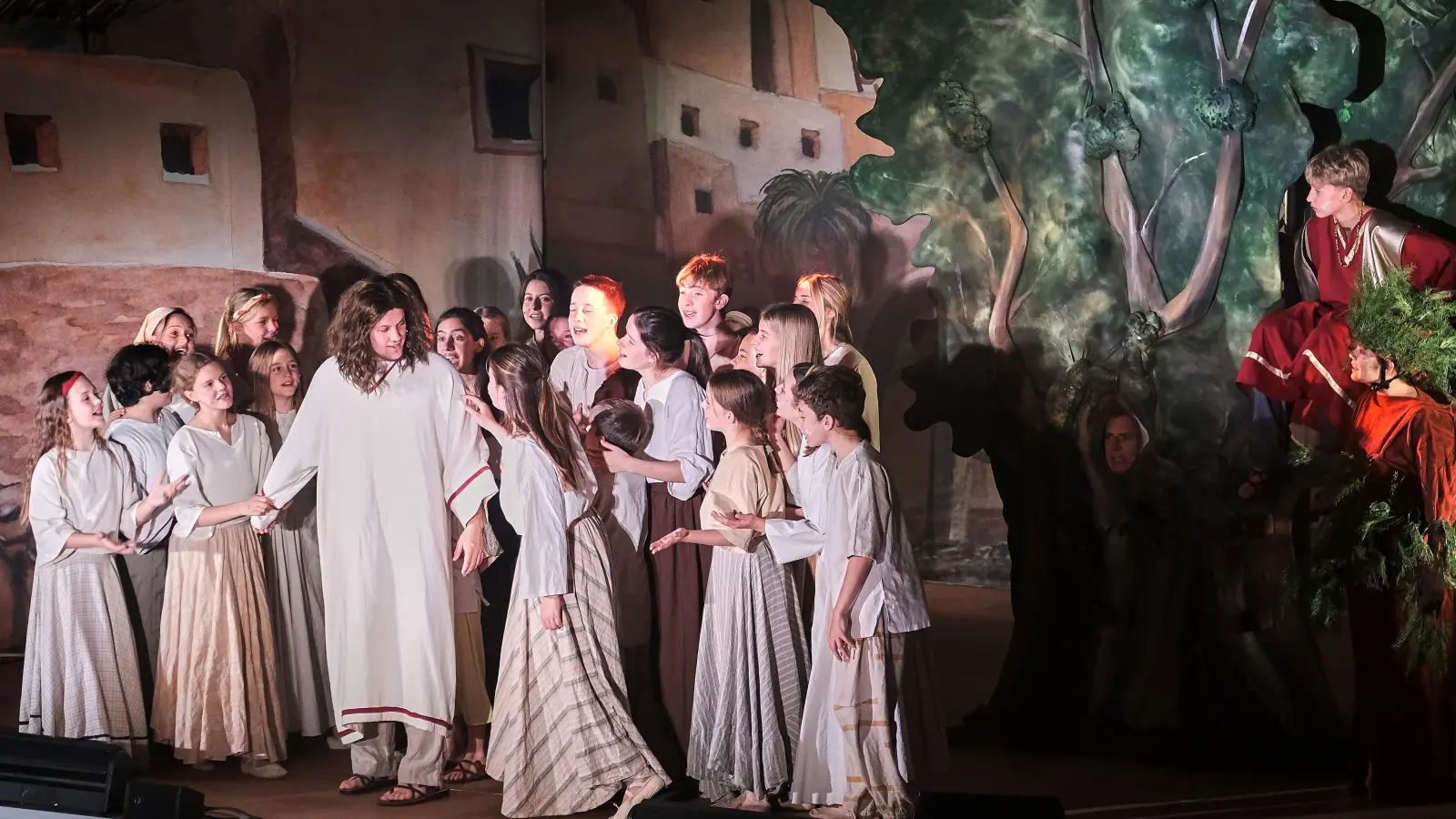 Zachäus (rechts, im Baum sitzend) beobachtet, wie Jesus von der Bevölkerung Jerichos begeistert empfangen wird - eine Szene des „Zachäus”-Musicals von Birgit Minichmayr, die so auch im Lukas-Evangelium vorkommt. (Bild: Peter Ringeisen)