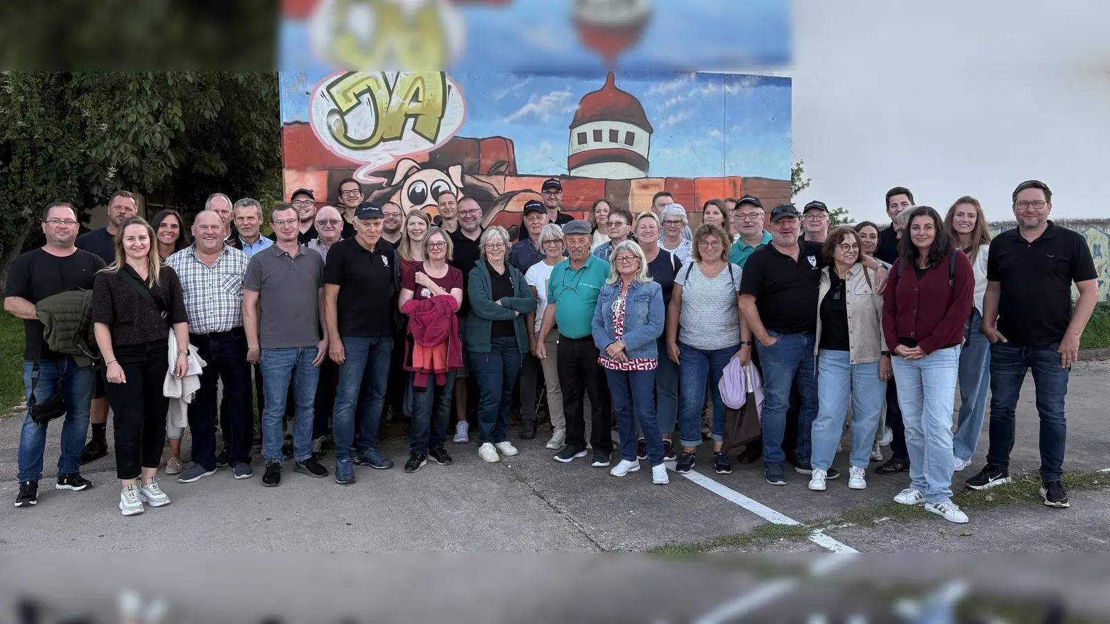 Ein Erinnerungsfoto gab es kurz vor der Abfahrt auf dem Parkplatz vor einem gemalten Turm der Stadtmauer im Hintergrund. (Bild: Franz Ficker)