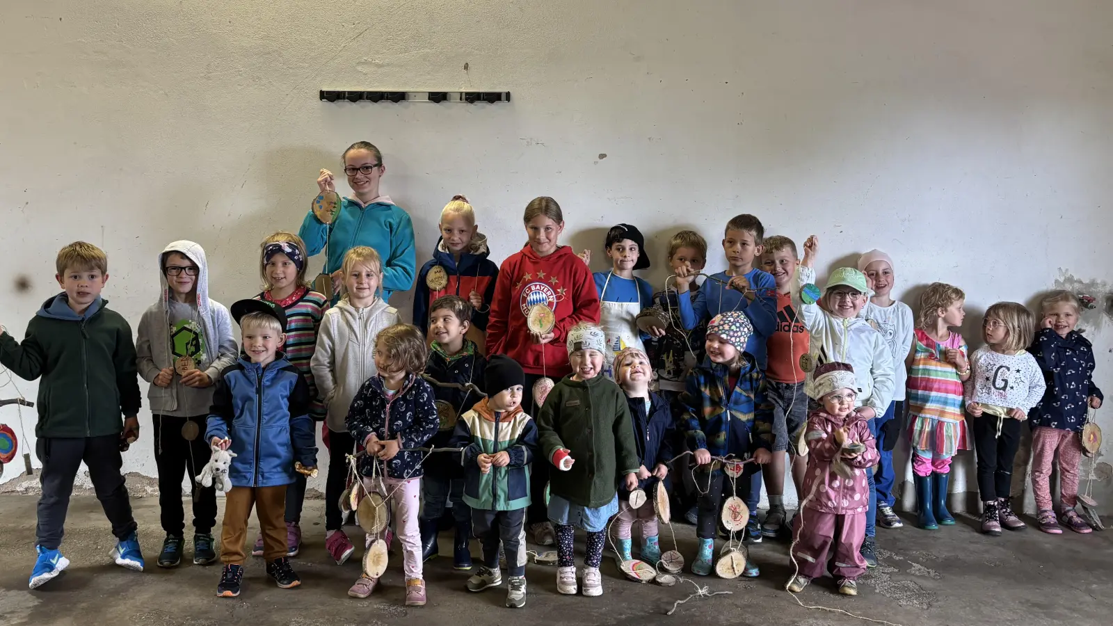 Stolz präsentieren die Kinder ihre gebastelte Baumscheiben-Deko. (Bild: Hannes Neumann )