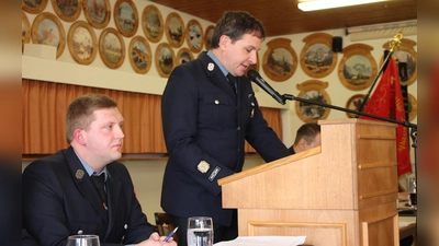 Kommandant Stefan Groß (stehend) und Vorsitzender Johannes Schwemmer blickten bei der Hauptversammlung im Preißacher Schützenheim auf ein an Aktivitäten reiches Jahr der Feuerwehr Burkhardsreuth zurück. (Bild: Bernhard Piegsa)