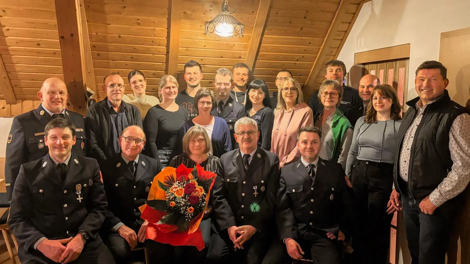 Neue Vorstandschaft mit Neuaufnahmen der FFW Vöslesrieth und Ehrengästen 1. Bürgermeister Rainer Rewitzer (vorne r.), Kreisbrandrat Marco Saller (3. von rechts), Kreisbrandinspektor Martin Weig (2.Reihe links) und Sieglinde Soukup mit Blumenstrauß (verlässt nach 24 Jahren Vereinsdienerin die Vorstandschaft).  (Bild: Annalena Brey)