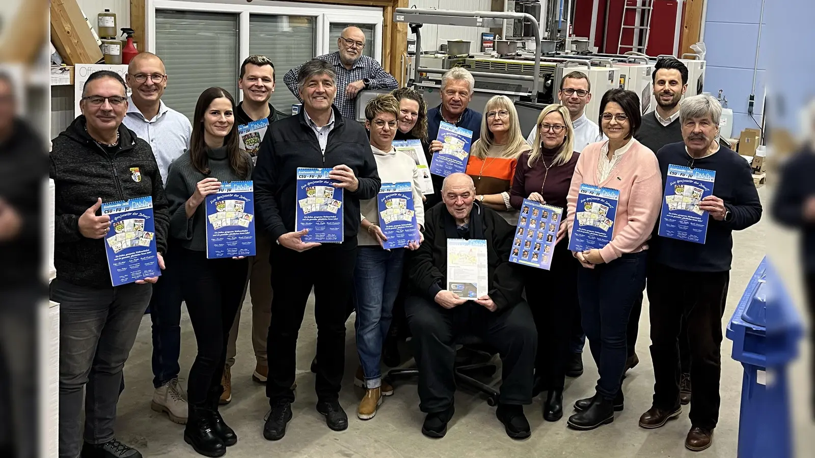Druckfrisch aus der Rotationsmaschine kommt der Kalender „Grafenwöhr 2026“. Die Stadtratsbewerber und Bürgermeister Edgar Knobloch stellten in der Druckerei Hutzler das begehrte Nachschlagewerk vor. (Bild: Bild: Tanja Hutzler)