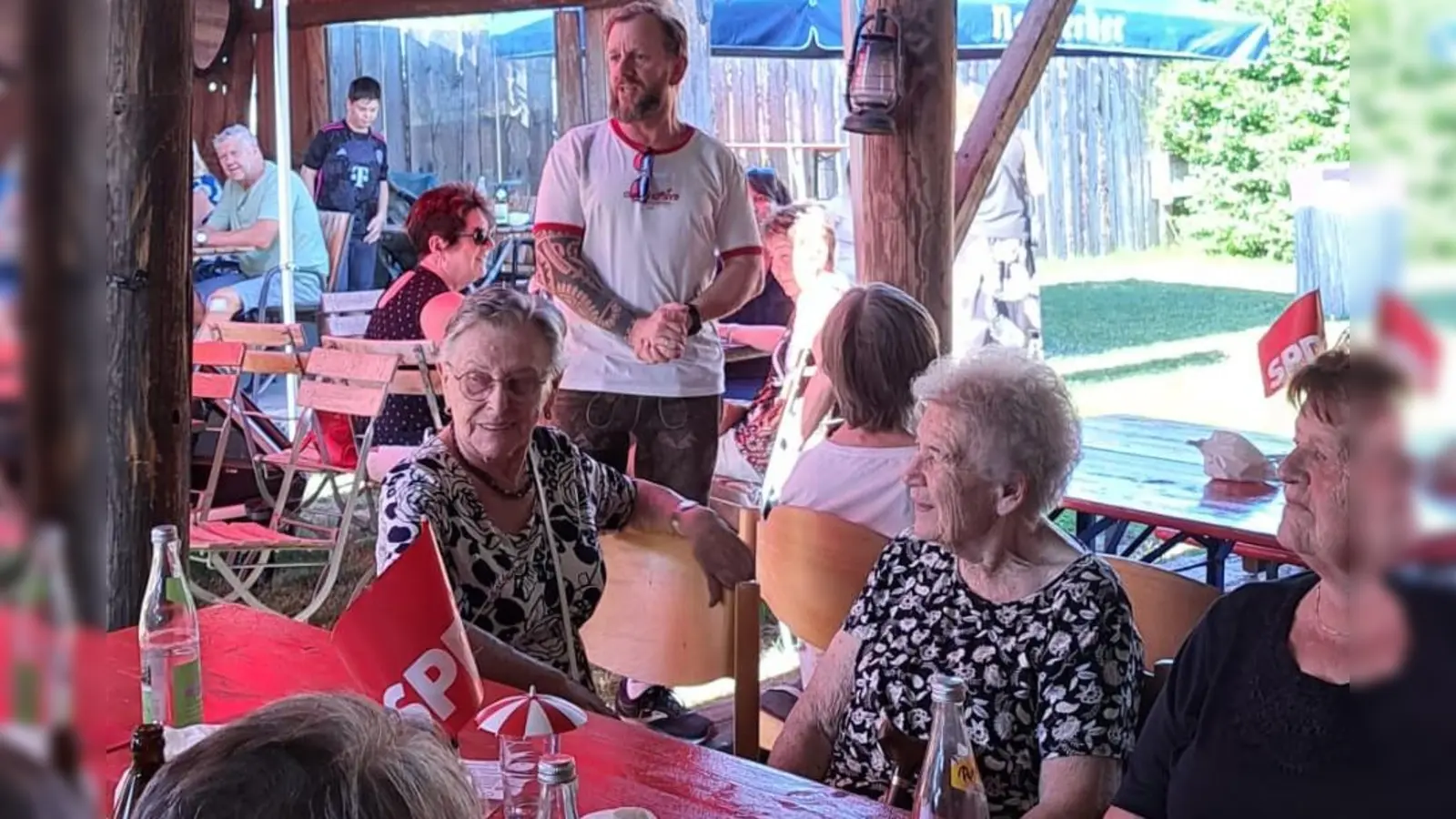 SPD-Vorsitzender Johannes Ambos (stehend) freute sich bei seiner Begrüßung über die vielen Gäste im Garten des Bikerstüberls Schwab. (Bild: Waltraud Lobenhofer)