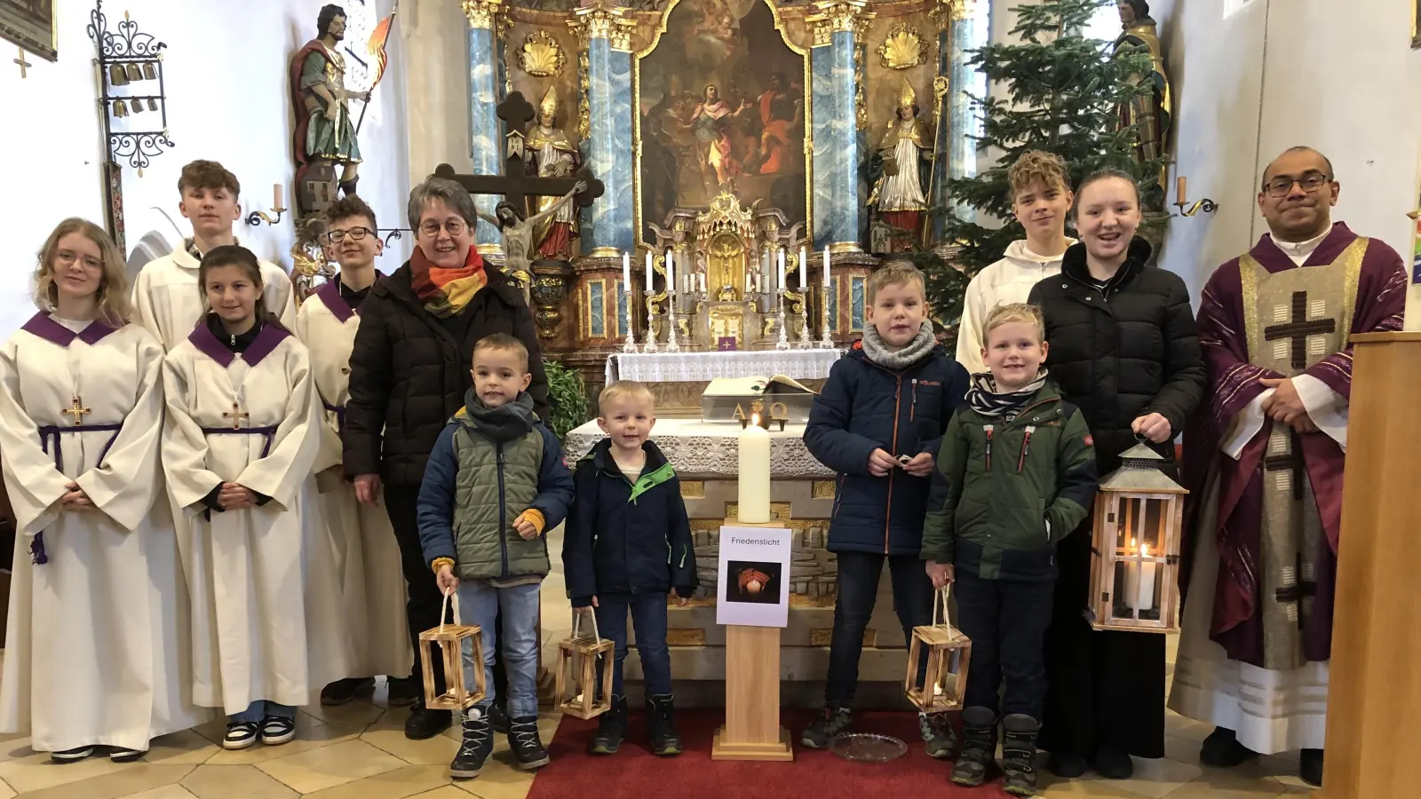 Stolz präsentieren die Kinder zusammen mit den Ministranten und Pfarrvikar Jimmy Joseph und Betreuerin Monika Krieger das Friedenslicht in der Kirche in Schlicht. (Bild: Christian Trummer)