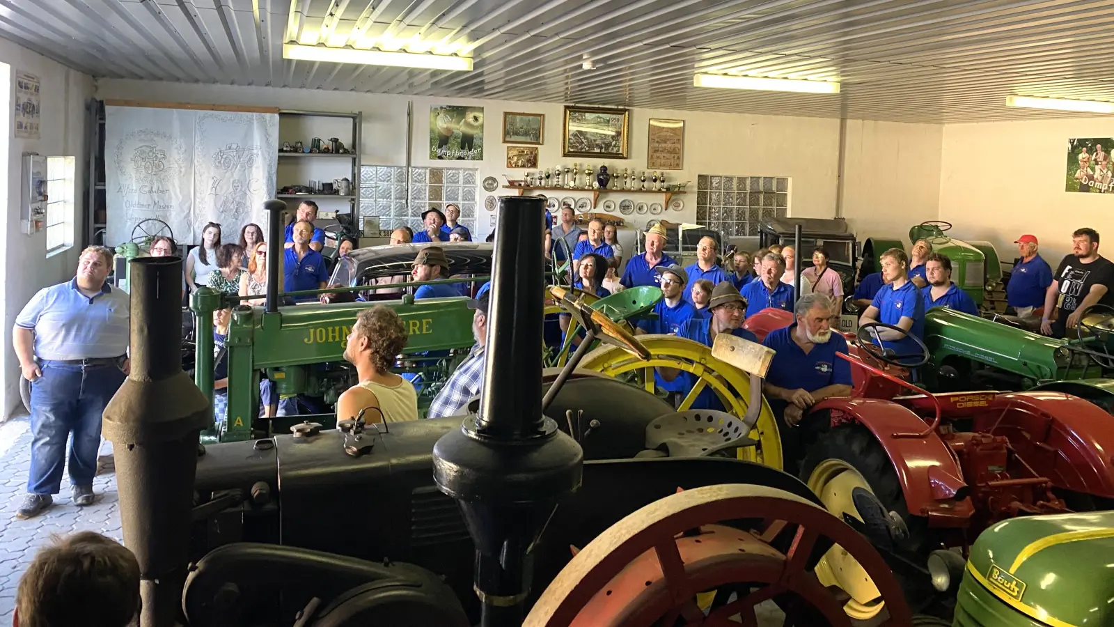 Die Moosbacher Oldtimerfreunde hören den Ausführungen von Christoph Ertl (Vorne Mitte - gelbes Shirt) im Woppenriether Museum interssiert zu. Der junge Oldtimerspezialist zeigt auch einen Film über den Gründer des Museums, Alfons Gollwitzer. (Bild: Franz Völkl)