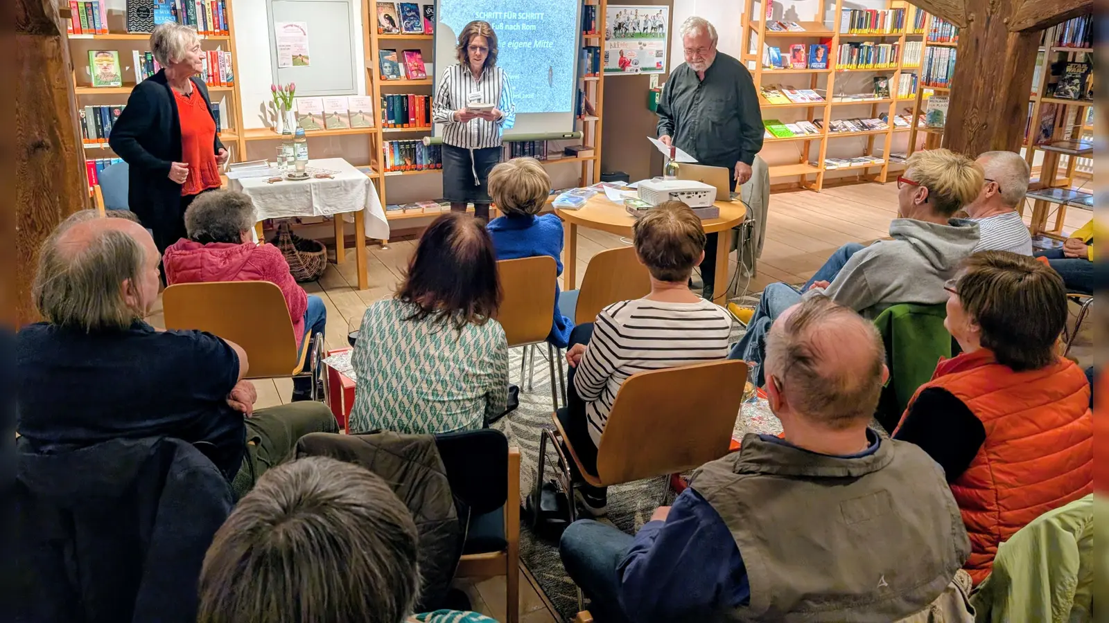 Andrea Burger begrüßt die Autorin Ingrid Haushofer und den Autor Gotthard Haushofer, sowie das Publikum bei der Lesung „Schritt für Schritt – zu Fuß nach Rom” in der Stadtbücherei. (Bild: Kristina Gebel )