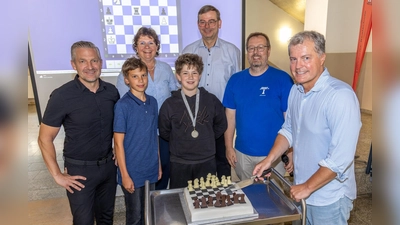 Schachgroßmeister Michael Bezold (vorne rechts) schneidet die Schachtorte an. Außerdem auf dem Bild (v.l.n.r.): Fördervereinsvorsitzender Martin Neuhaus, Konstantin Hüttner, Schulleiterin Irene Sebald, Korbinian Meggenrieder sowie die Schachlehrer Rudolf Lohwasser und Johannes Paar. (Bild: Tobias Neubert)
