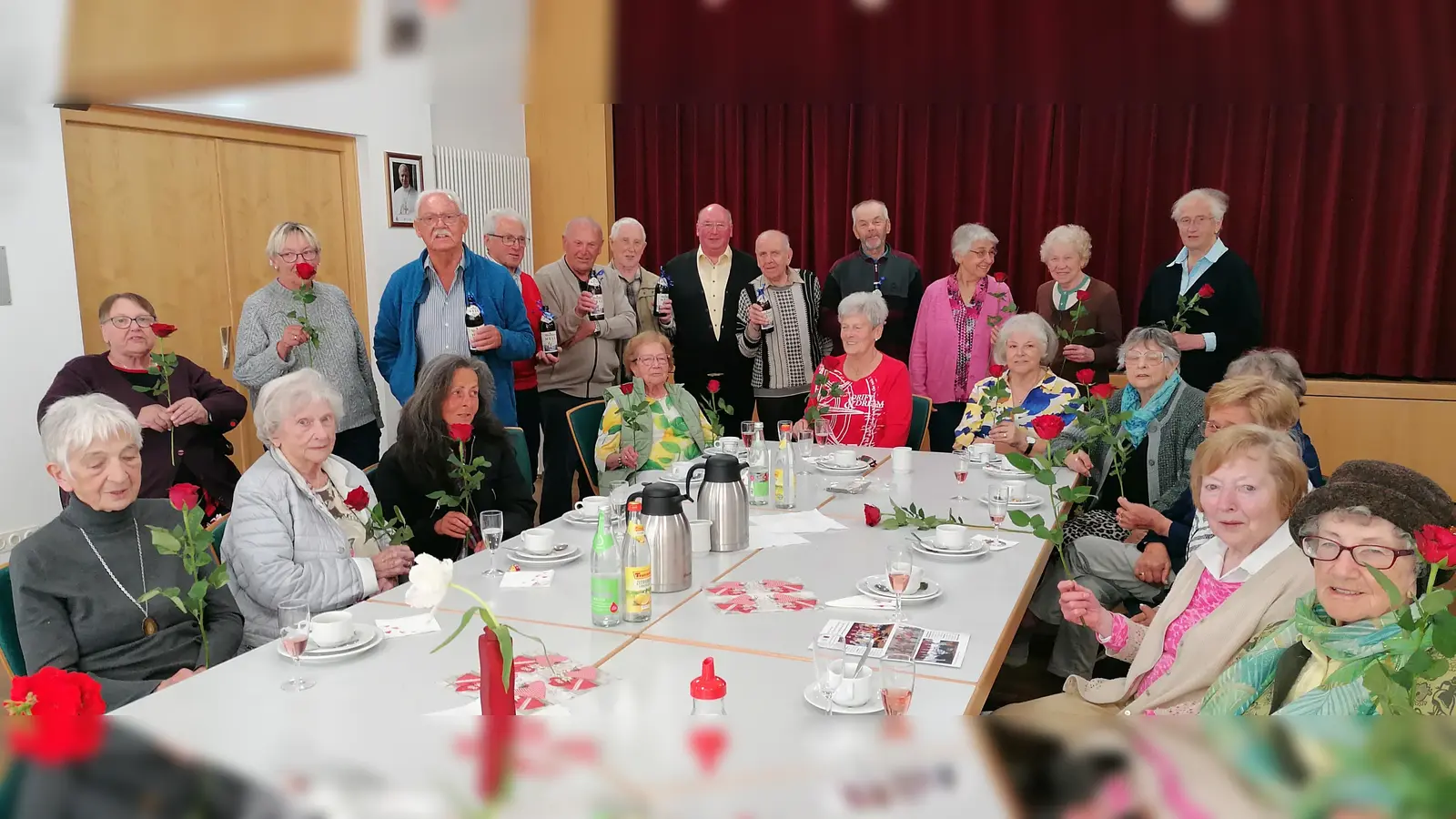 Viele der Seniorentreff-Teilnehmer in froher Runde mit Rosen und Bierchen in der Hand. (Bild: Angelika Veit )