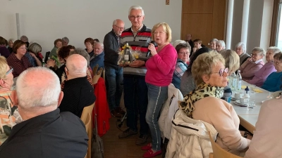 Seniorenbeauftragte Gabriele Beck (links stehend) bedankte sich mit einem kleinen Präsent bei Hans Lobinger (rechts stehend) für seine schöne und aufschlussreiche Bilderschau über Alt-Schwarzenfeld  (Bild: Silvia Beck)