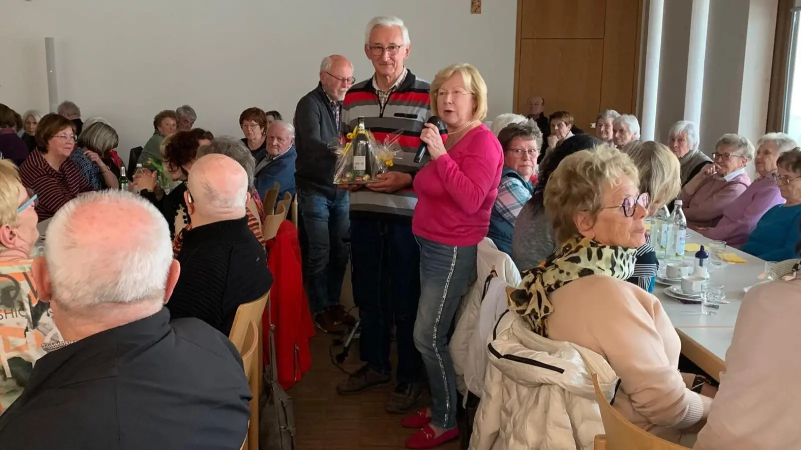 Seniorenbeauftragte Gabriele Beck (links stehend) bedankte sich mit einem kleinen Präsent bei Hans Lobinger (rechts stehend) für seine schöne und aufschlussreiche Bilderschau über Alt-Schwarzenfeld  (Bild: Silvia Beck)
