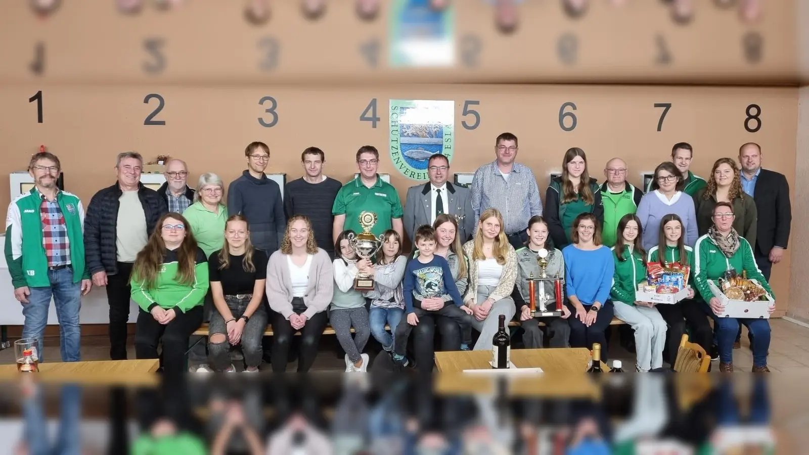 Gesamtfoto aller Sieger des Gaudamen- und Ü40-Schießens 2025. <br>Erster Sportleiter Florian Frischmann (stehend, Achter von rechts), Stellvertreter Karl Bauriedl (Erster von links), sowie Erster Bürgermeister Reiner Gäbl (stehend, Zweiter von links) und dessen Stellvertreter Thomas Kleber (stehend, Erster von rechts) gratulierten. (Bild: Dominik Brenner)