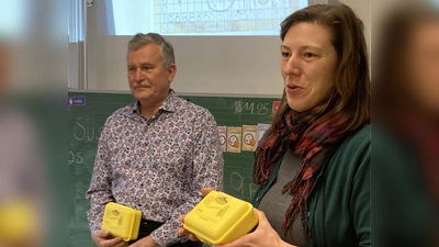 Wilhelm Weiß und Lissy Waldeck vom Förderverein Pro Etzenricht stellen die Bio-Brotboxen den Kindern der 1. Klasse vor, bevor sie diese verteilen. (Bild: Gabriela Bäumler)