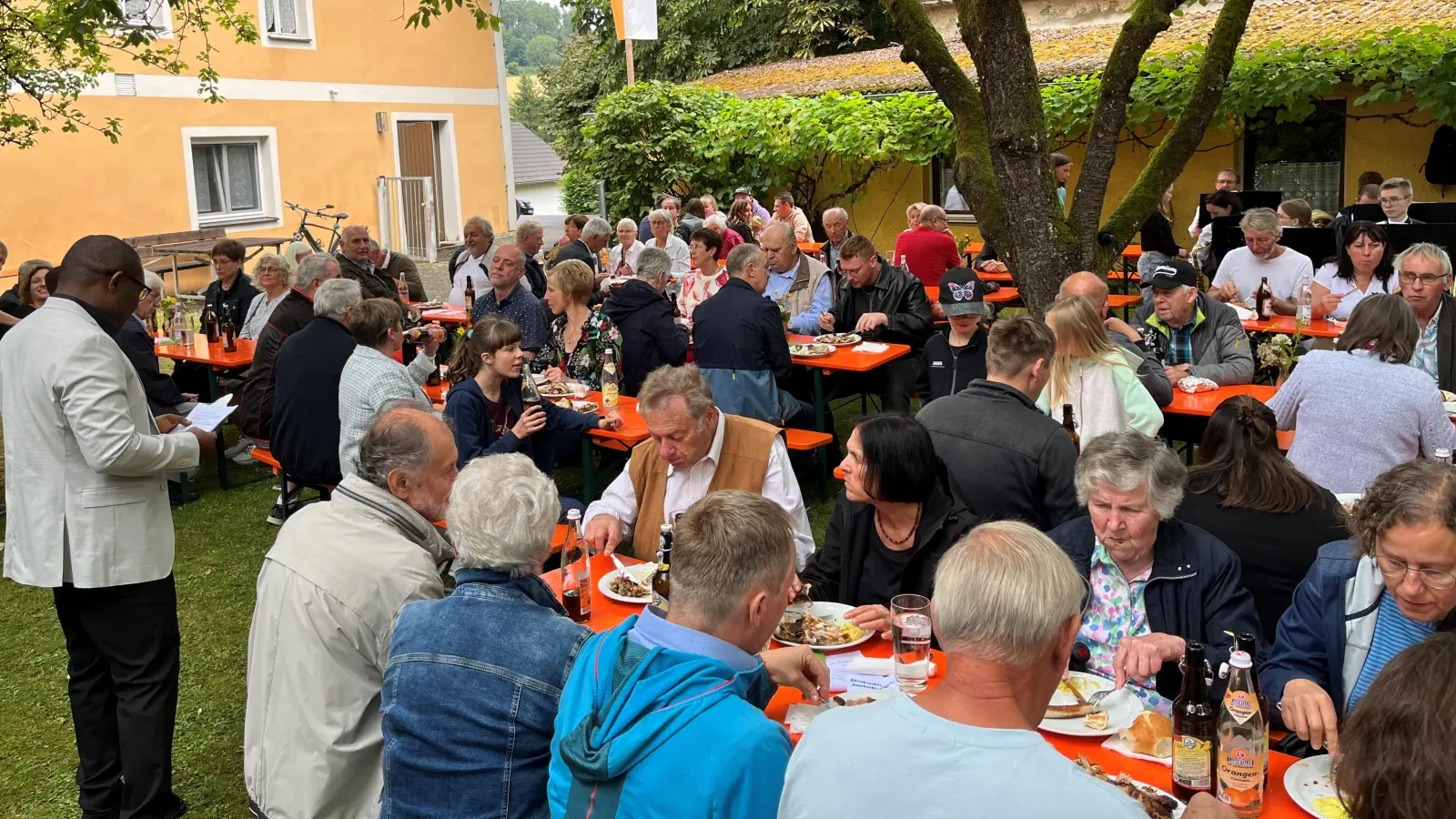 Pfarrer Emmanuel Okoro (stehend links) freute sich über den sehr guten Besuch beim Pfarrfest in Unterauerbach anlässlich des Weihetages der Kirche St. Nikolaus und dankte allen, die zum Gelingen beigetragen haben. (Bild: Franz Grabinger)