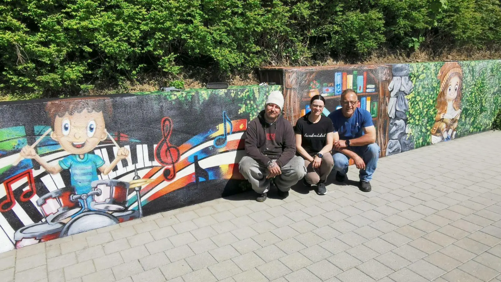 Kunstmaler Jerry (links) verwandelte die kahle Mauer im Pausehof der Grundschule in ein Kunstwerk. (Bild: Karl Ziegler)