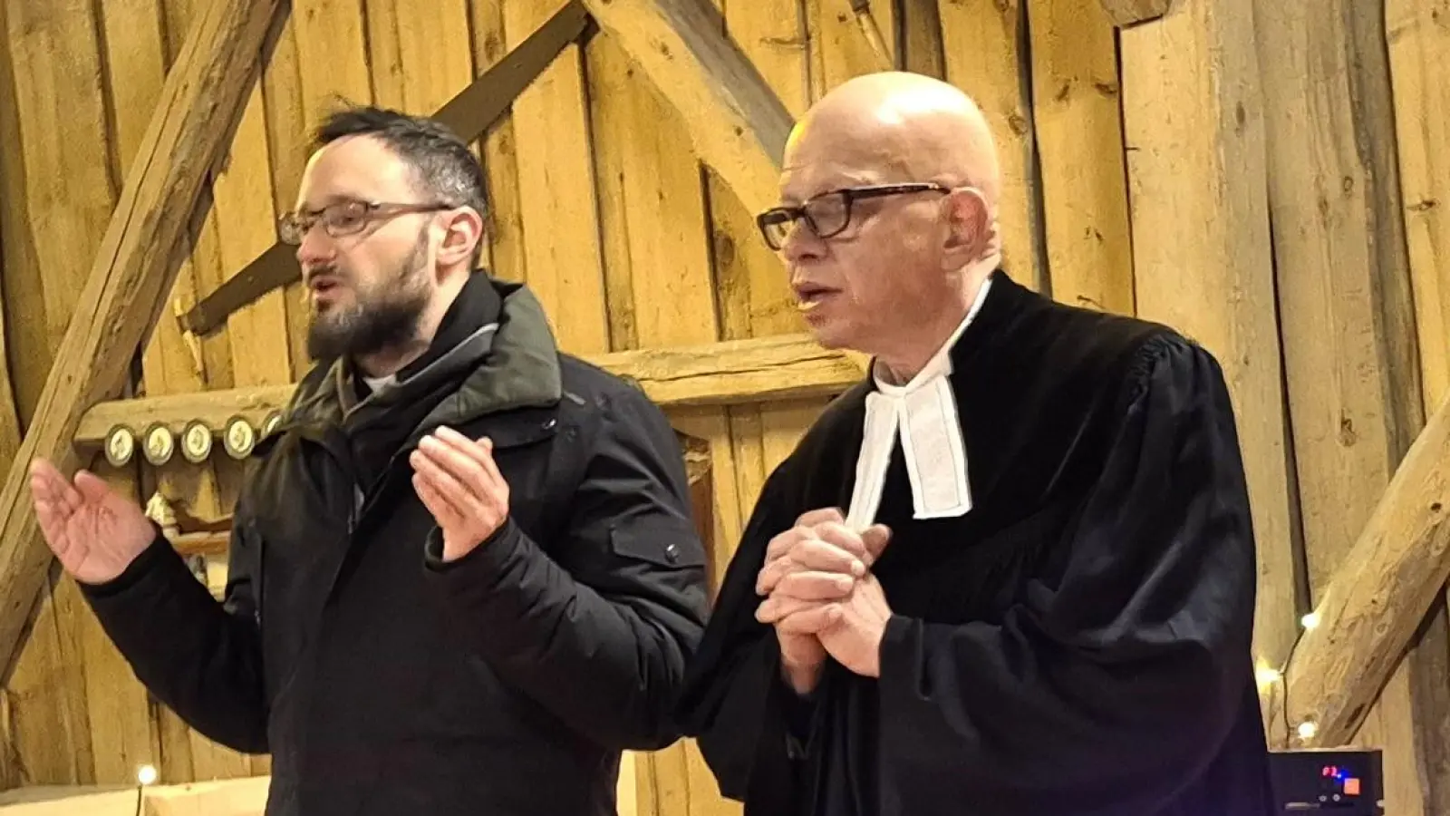 Pfarrer Johannes Arweck (links) und Pfarrer Thomas Schertel, im weihnachtlich dekorierten „Altarnereich”, im Dorfstadel in Götzendorf, bei der ökumenischen Weihnachtsandacht. (Bild: Norbert Weis )