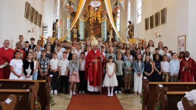 Nach dem Festgottesdienst stellte sich Bischof Dr. Rudolf Voderholzer inmitten der 52 Firmlinge zu einem Erinnerungsfoto in der Pfarrkirche St. Georg – unter den in der Firmvorbereitung angefertigten Feuerzungen mit den Namen der Jugendlichen. Links Diakon Dieter Gerstacker und Pfarrvikar Jimmy Joseph, rechts Stadtpfarrer Hruday Madanu. (Bild: Christian Trummer)