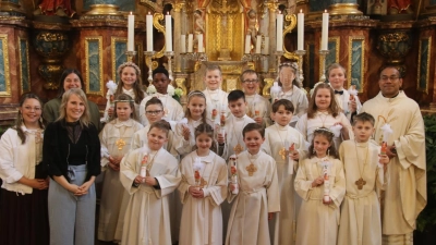 17 Kinder aus Schlicht und Sorghgof empfingen in der Pfarrkirche St. Georg in Schlicht die Erstkommunion. Zusammen mit Pfarrvikar Pater Jimmy Joseph (re.) und den Tischmüttern (v. li.) Laura Kohl, Anja Wendl und Steffi Kohl stellten sie sich nach dem Gottesdienst vor dem Hochaltar zum Erinnerungsfoto auf. (Bild: Werner Prechtl)