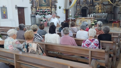  Diakon Ulrich Wabra (links stehend) erläuterte fachkundig den Interessierten aus der Pfarreiengemeinschaft Leuchtenberg, Michldorf, Roggenstein die Geschichte seiner Heimat-Pfarrkirche Oberviechtach. (Bild: Claudi Rupprecht)