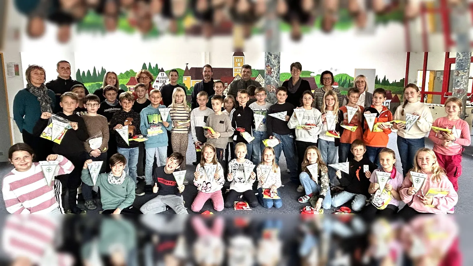 die Viertklässler bei der Wimpelübergabe in der Aula, mit den Polizeibeamten, den Klassenlehrerinnen, der Schulleitung und den Gästen (Bild: Norbert Weis)