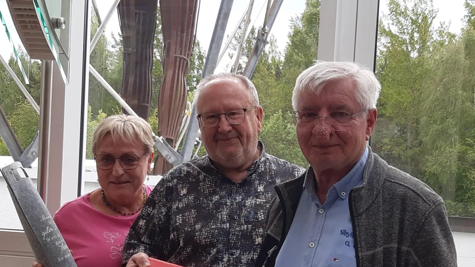 Josef Hofbauer überreichte dem Sibyllenbad-Leiter und Papst-Fan ein Buch über die Oberpfalz sowie den Lieblingswein des ehemaligen Papstes Johannes Paul als Abschiedsgeschenk. (von links): Ute und Josef Hofbauer mit Gerhard Geiger im Restaurant „Sibylle“ im Sibyllenbad. (Bild: Barbara Bannert)