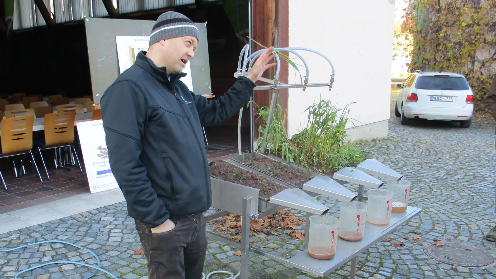 Michael Lukas (Wasserbeauftragter vom AELF) erklärt am Regensimulator, wie sich Starkregenereignisse auf unterschiedliche Böden(bewüchsen) auswirken. (Bild: Valentin Rumpler)