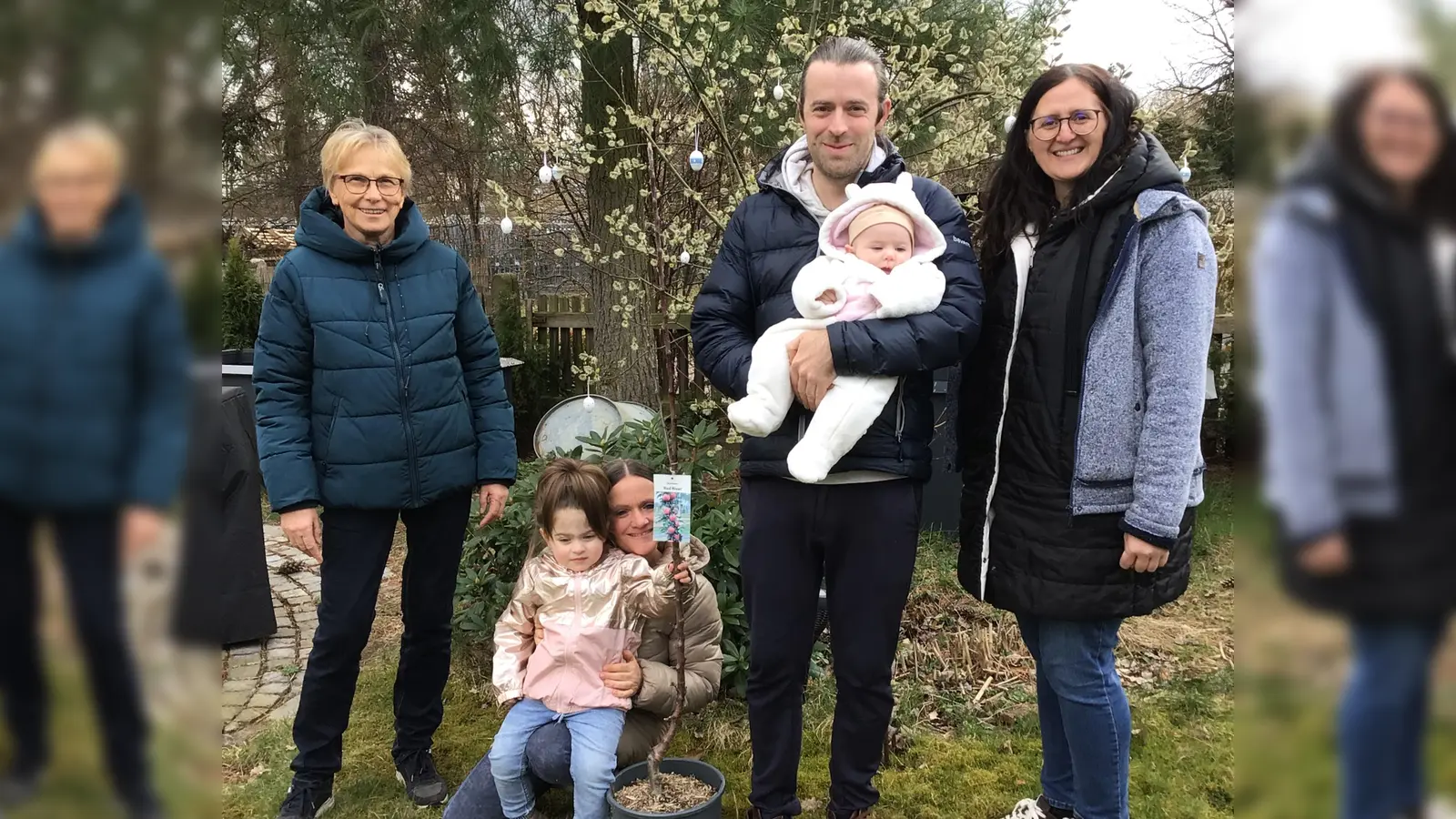 Maria Hammerl (li.) und Martina Spindler (r.) vom OGV Wernberg-Köblitz überreichen an Familie Pum (Mitte) den Apfelbaum für ihre jüngste Tochter Eva.  (Bild: Sigi Spindler)