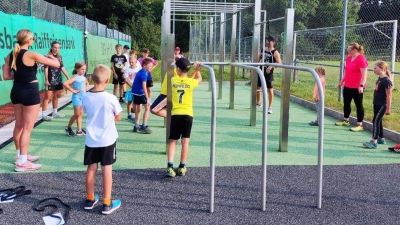Egal, ob an den Stangen oder mit dem Körpergewicht: Die Übungen machten nicht nur Spaß, sondern gingen auch auf die Muskeln. Mit Unterstützung von Bodylates- Coach Sandra Pittner (links) probierten die Kinder und Jugendlichen die neue Calsithenics- Anlage in Vorbach beim FWG- Kinderferienprogramm aus.  (Bild: Dominik Eckert )