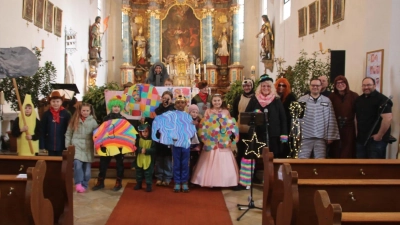 Monika Krieger (Mitte hinten), die angehenden Kommunionkinder und die Band 1-Way (rechts) gestalteten einen bunten Faschingsgottesdienst in der Pfarrkirche Schlicht (Bild: Christian Trummer)