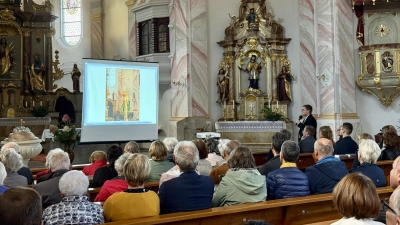 Kaplan Matthias Merkl blickt mit Hilfe eines Diavortrags gemeinsam mit der Pfarreiengemeinschaft auf seine Primiz im vergangenen Jahr zurück. (Bild: Marie Bertelshofer)