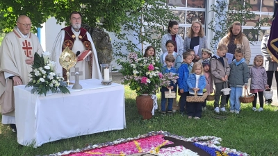 Ein aufwendig gestalteter Blumenteppich schmückt den Altar der Feuerwehr und der Vereine. Am Altar (von links) Pater Edward Lipiec und Diakon Franz-Josef Reck. Daneben die Kindergartenkinder. (Bild: Sonja Müller)