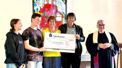 Ein Höhepunkt des Gottesdienstes ist die Übergabe eines symbolischen Schecks durch Pfarrer Klaus Stolz (rechts) und zwei Konfirmierte (links) an das Pfarrerehepaar Milton Jandrey ud Márcia Hülle (Mitte). (Bild: Brigitte Lang)