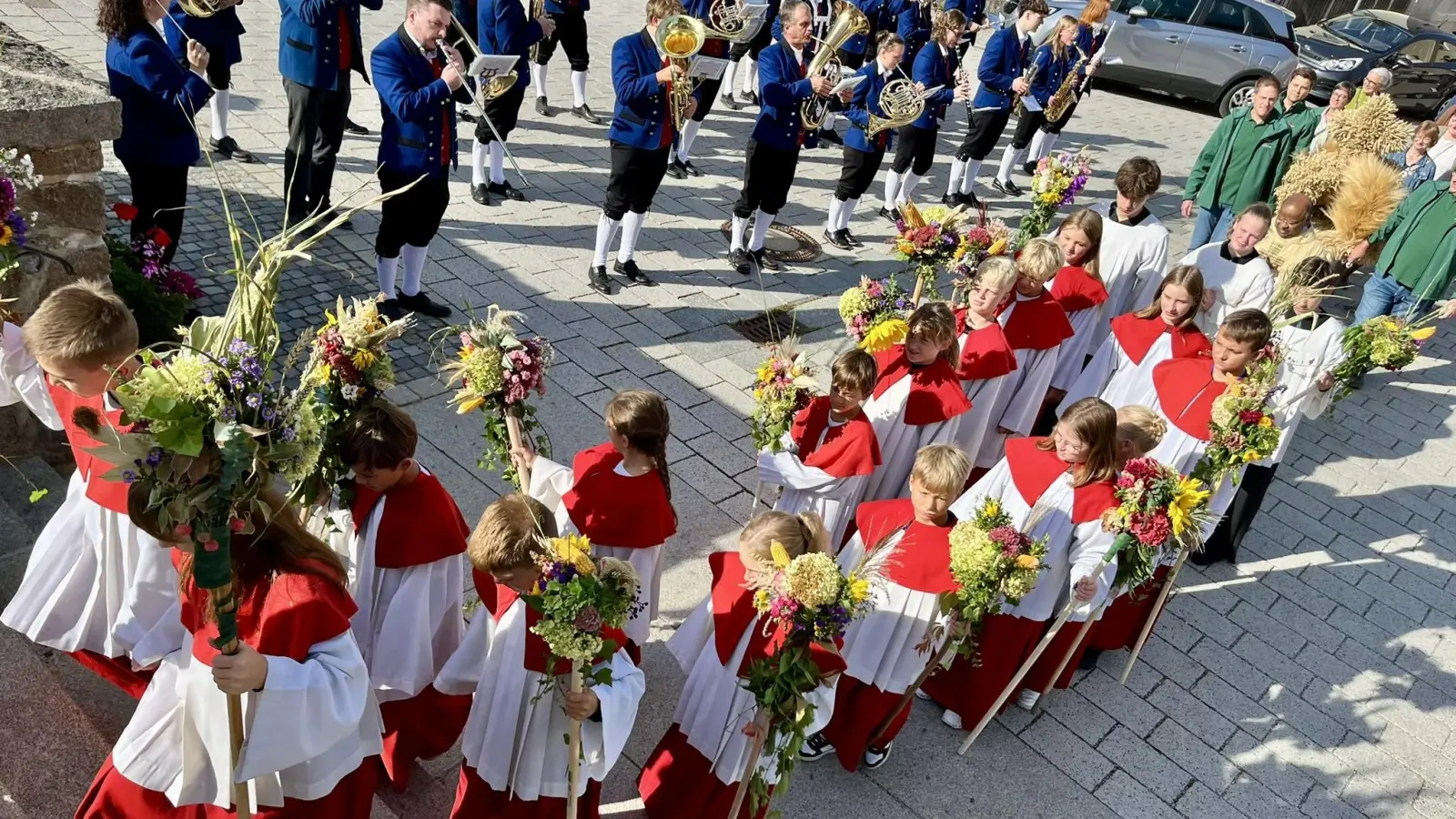 Die Wutschdorfer Ministranten mit ihren Erntebuschen. Im Hintergrund das Orchester des Musikvereins Freudenberg. (Bild: Ina Piehler)