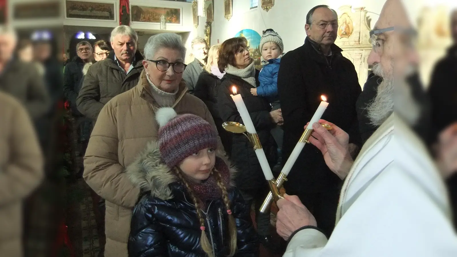 Vom symbolischen Kerzenlicht an Lichtmess eingerahmt spendet Pfarrer Josef Dotzler jedem Erwachsenen sowie den Kindern den Blasiussegen. (Bild: Michael Götz)