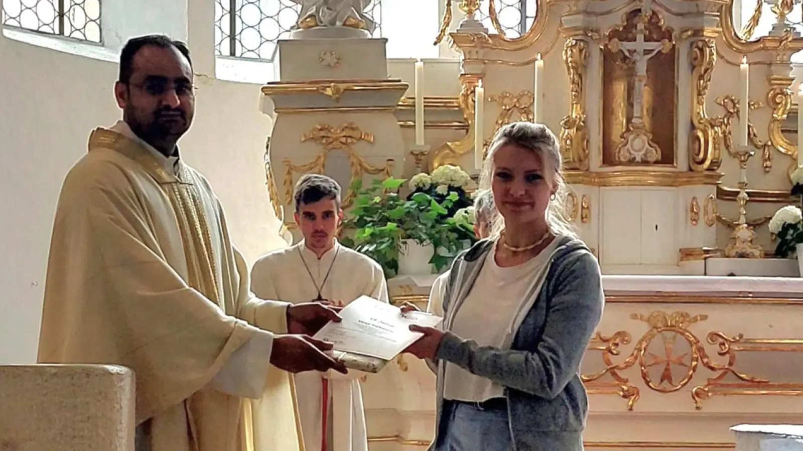 Pfarrvikar Rajesh Yeruva überreicht langjähriger Ministrantin Vicki Vießmann eine Urkunde der Diözese Eichstätt und ein Dankeschön der Pfarrei Kastl (Bild: Theresia Otterbein)