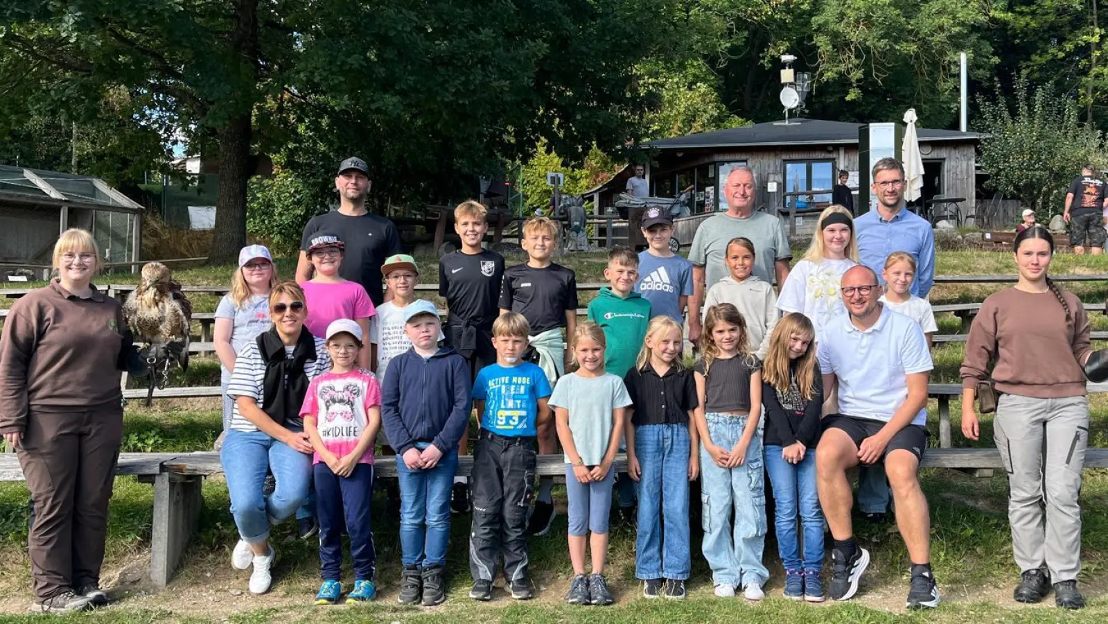 Die Teilnehmer des SPD-Ferienprogramms 2025 zusammen mit den Verantwortlichen des Ortsvereins um Vorsitzenden Markus Wenisch (sitzend vorne rechts) und den Falknerinnen des Greifvogelparks (links und rechts) (Bild: Wolfgang Pötzl)