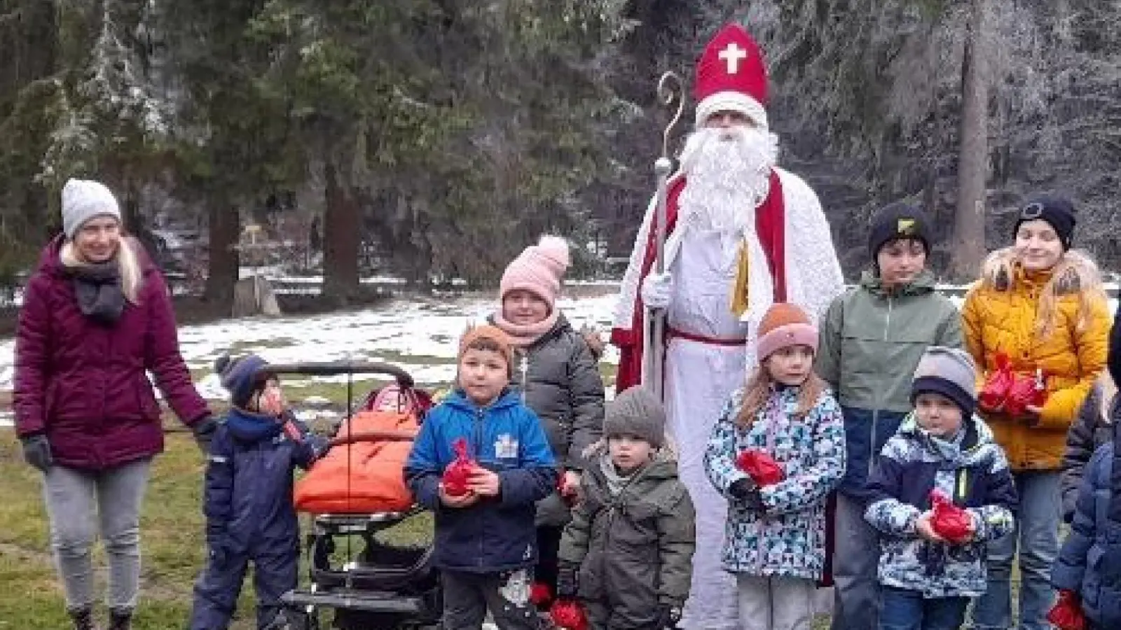 Nach der Messe stellten sich besonders Mutige mit Bischof Nikolaus zu einem Erinnerungsfoto. Im Hintergrund sieht man rings um die Kirche die Bäume mit Raureif und Schnee. (Bild: Rosa Schöner)