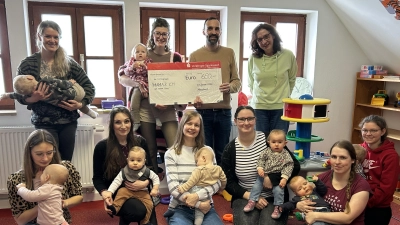 Bürgermeister Armin Bulenda und die erste Vorsitzende des Kath. Frauenbundes Moosbach, Angelika Hierold (stehend, 1. von rechts) übergeben Spenden an die neue Leiterin Julia Weiß (stehend, 2. von links). Auf dem Foto freuen sich die Mütter gemeinsam mit ihren Kindern über die Unterstützung für die Mutter-Kind-Gruppe „Mama &amp; Ich” (Bild: Claudia Rieß)