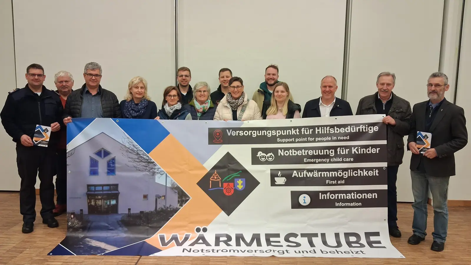 Mit einem auffälligen Bauzaunbanner würde im Fall der Fälle auf die Wärmestube im Vitusheim hingewiesen, so dass auch ortsunkundige MitbürgerInnen die Anlaufstelle finden könnten. V. l. federführender Kommandant der Schnaittenbacher Feuerwehren Michael Werner und Vitusheim-Hausmeister Reinhold Rösch, die Vertreter der kirchlichen Organisationen mit v. r. Stadtpfarrer Helmut Brügel, Pfarrgemeinderatssprecher Martin Bergmann und Bürgermeister Marcus Eichenmüller.  (Bild: Uli Reindl)