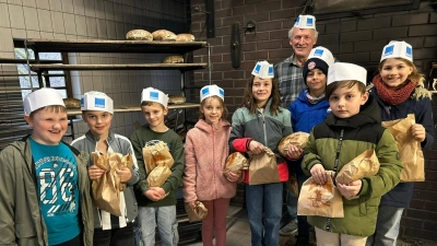 Mit je einem frischen Brot, dass die Kommunionkinder mit gebacken hatten, verabschiedeten sie sich beim Bäckermeister (Vierter von rechts) mit einem gemeinsamen lautstarkem Danke. (Bild: Katrin Baier)