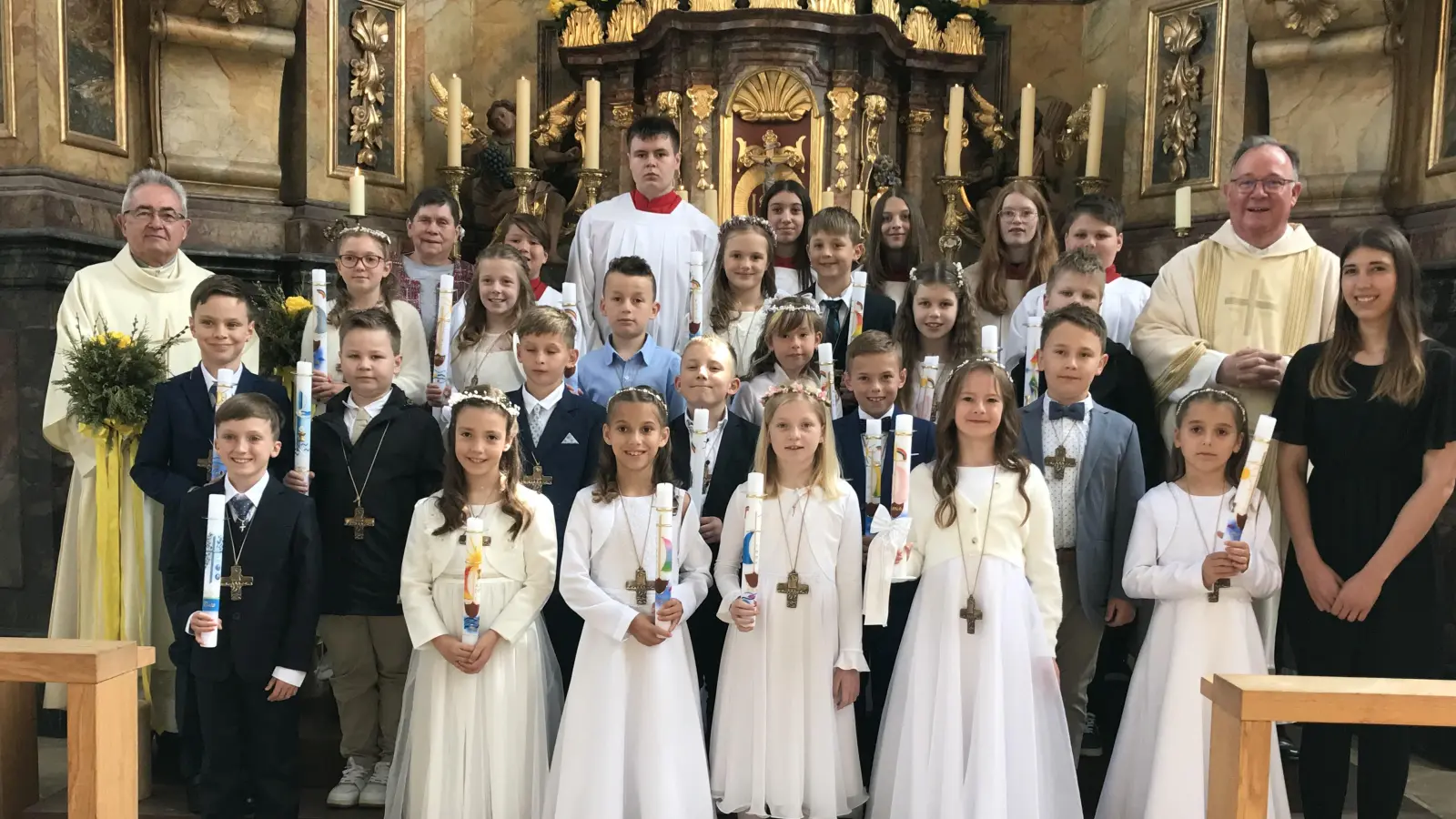 Die 20 Erstkommunikanten mit Diakon Dieter Gerstacker, Mesnerin Rosmarie Rauch, Pfarrer Michael Birner, Lehrerin Tara Malchin und MinistrantInnen. (Bild: Marianne Moosburger)