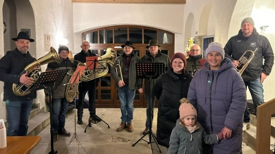 Vor der Bescherung an Heilig Abend bereicherten die Werkstattmusikanten um Leiter Marco Procher (li) ohne Gage und ehrenamtlich übernahmen Markträtin Laura Roth im Beisein von Hannah und Madeleine Hammerl (vorne v.r.) den Ausschank. (Bild:  Christian Sterr)